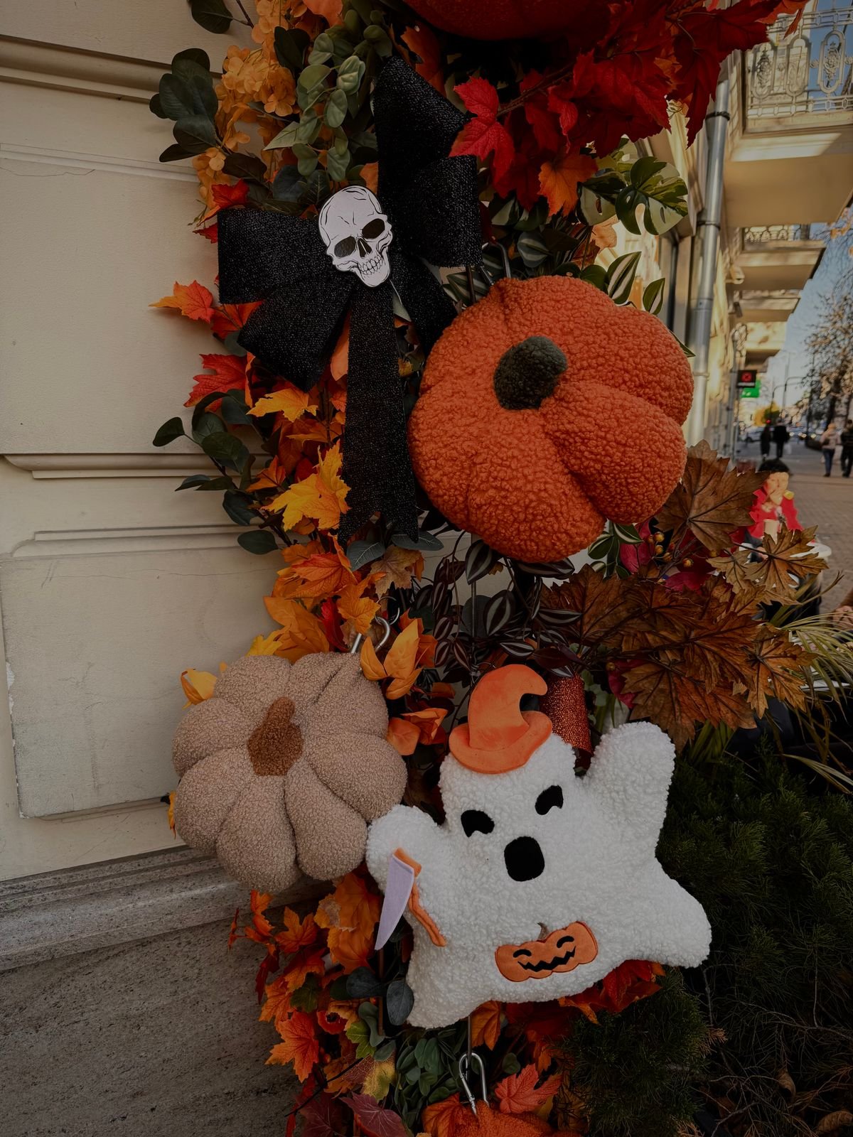 halloween wreath with autumn leaves and black bat picks on a front door
