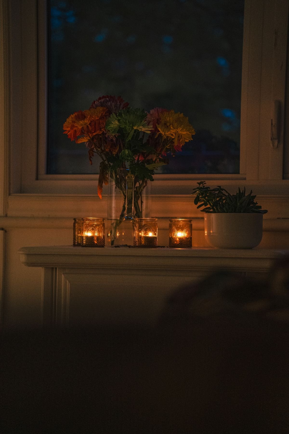 Cluster of glowing candles in a cozy autumn living room, warm fall home decor lighting