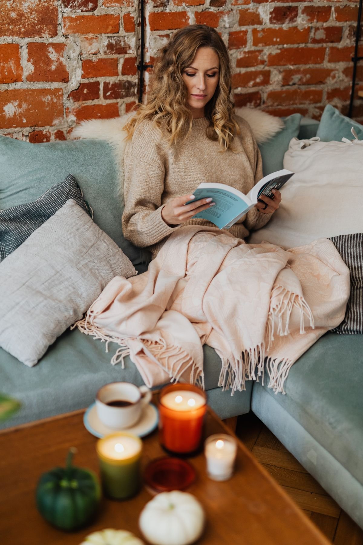 Sofa draped with a plaid throw blanket in autumn colours, cozy fall living room decor