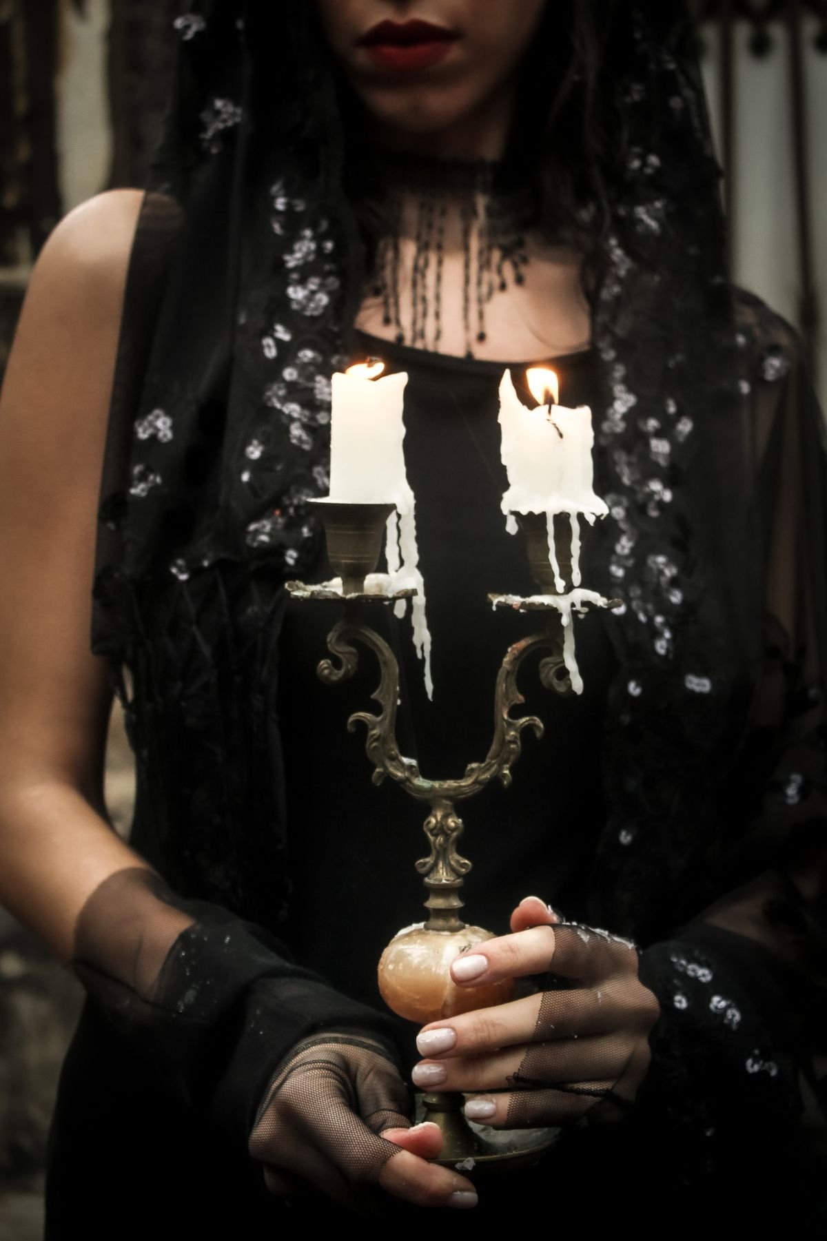 Black candelabra with candles on a dark mantel