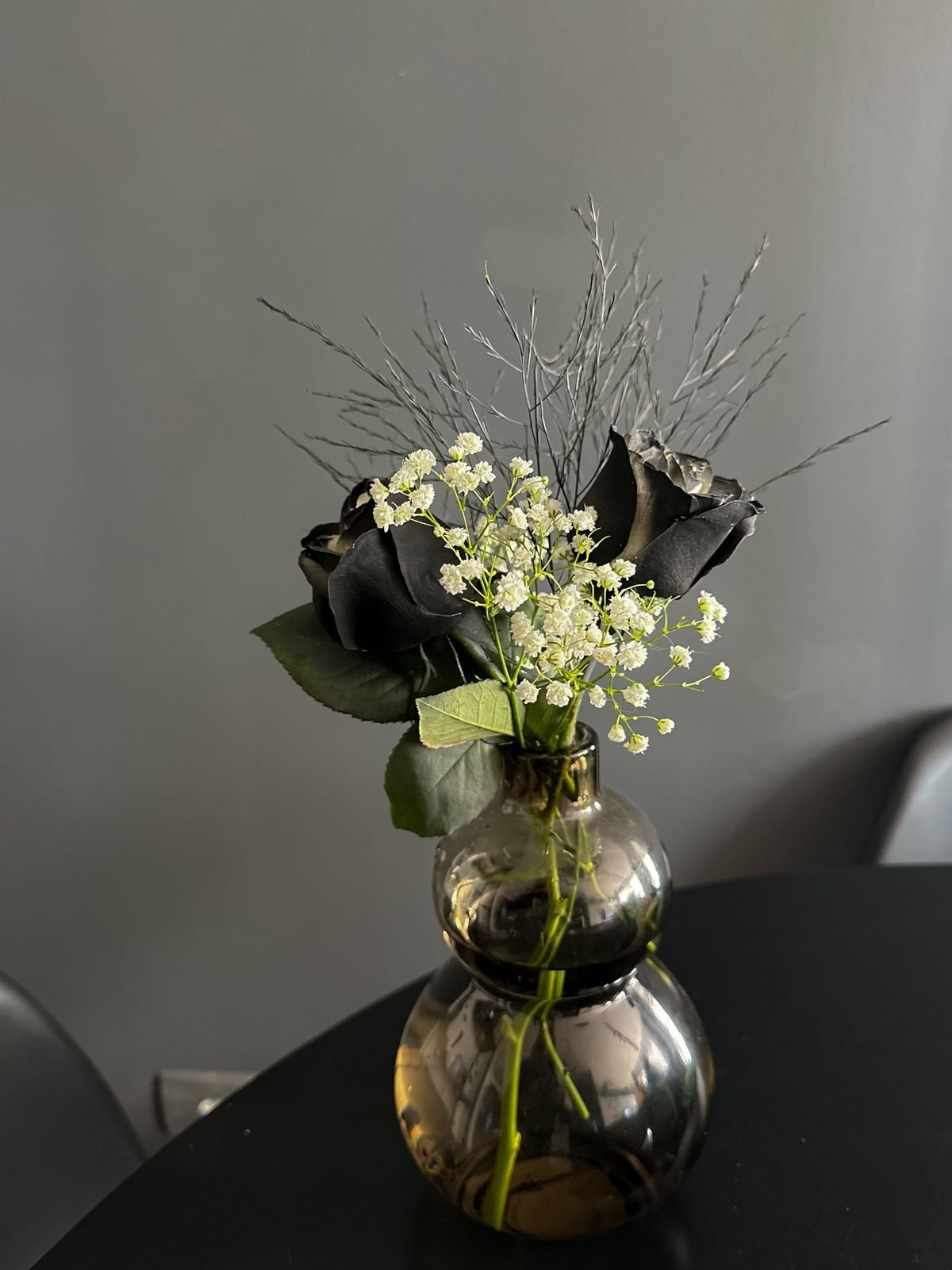 Black roses arranged in a dark vase