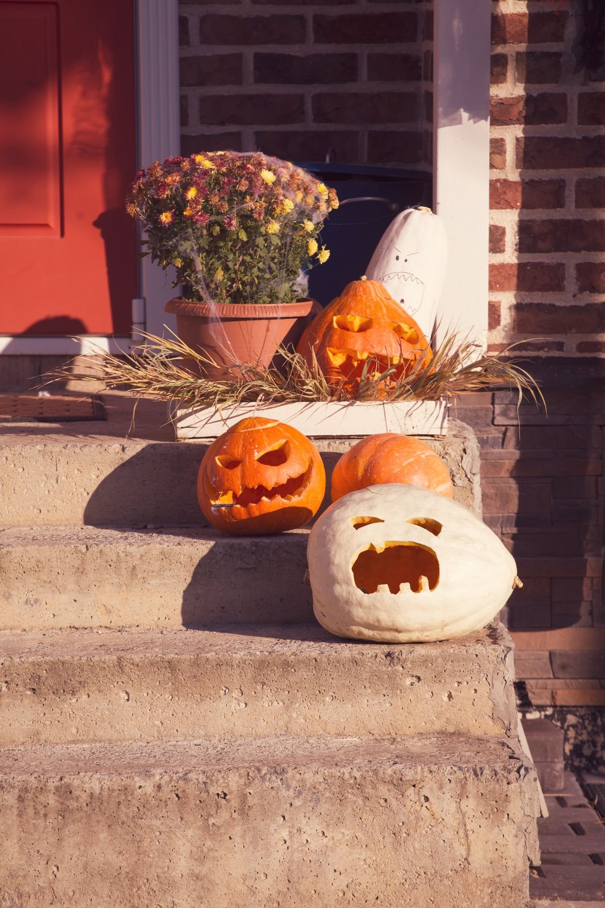 Pumpkins of different sizes lined along front porch steps for halloween home decor