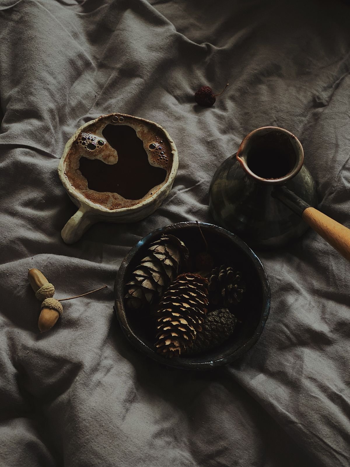 Wooden bowl of acorns and pinecones with tealights for autumn decor