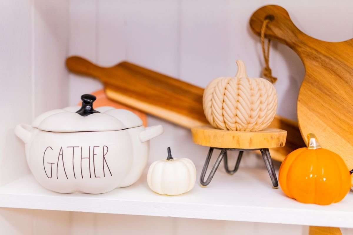 Decorative shelf styled with stacked books pumpkin and black candle autumn