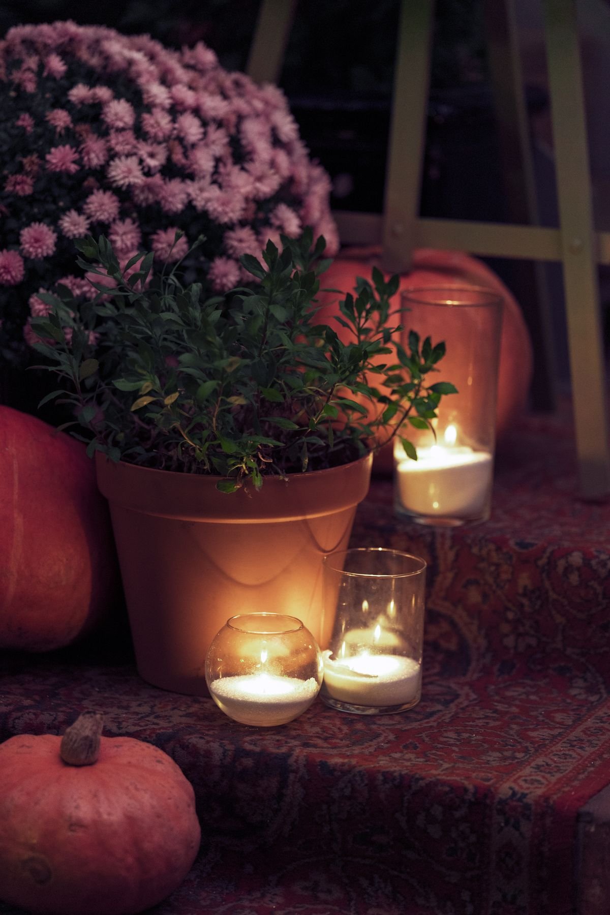 Balcony with potted mums and warm string lights autumn evening
