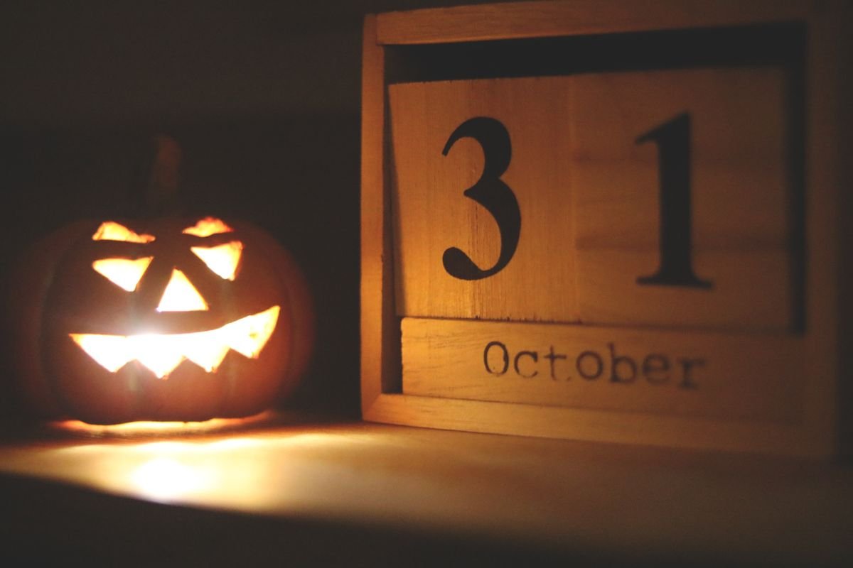 Jack-o-lantern lamp glowing on a home office desk near an october calendar
