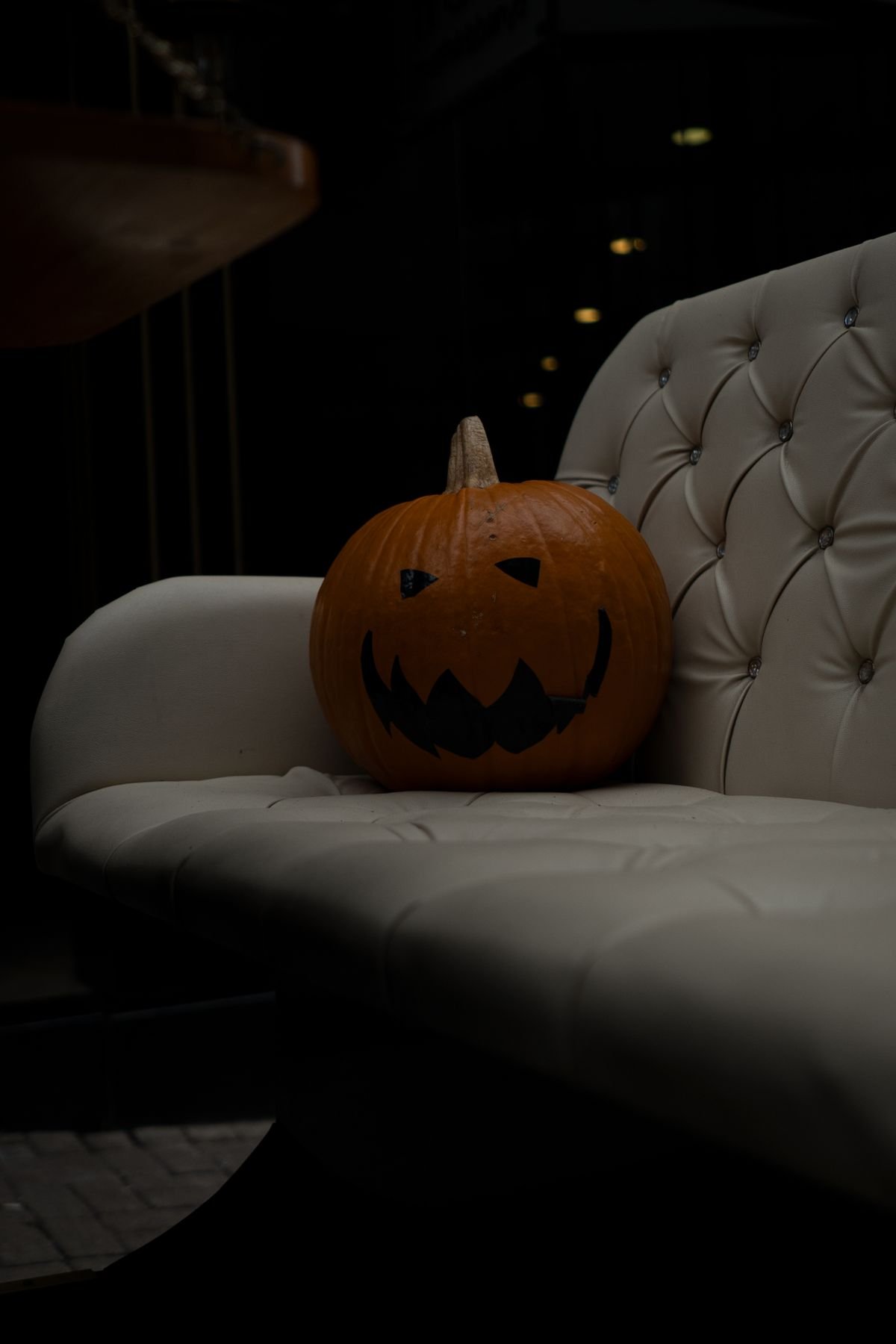 Carved jack-o'-lantern sitting on the arm of a white sofa for halloween