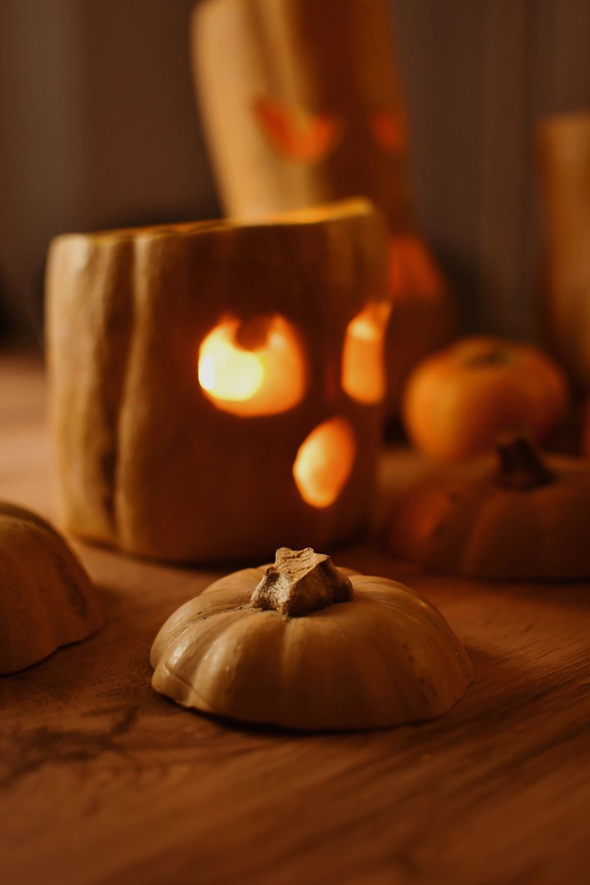 Carved pumpkins glowing in candlelight beside a living room window at dusk