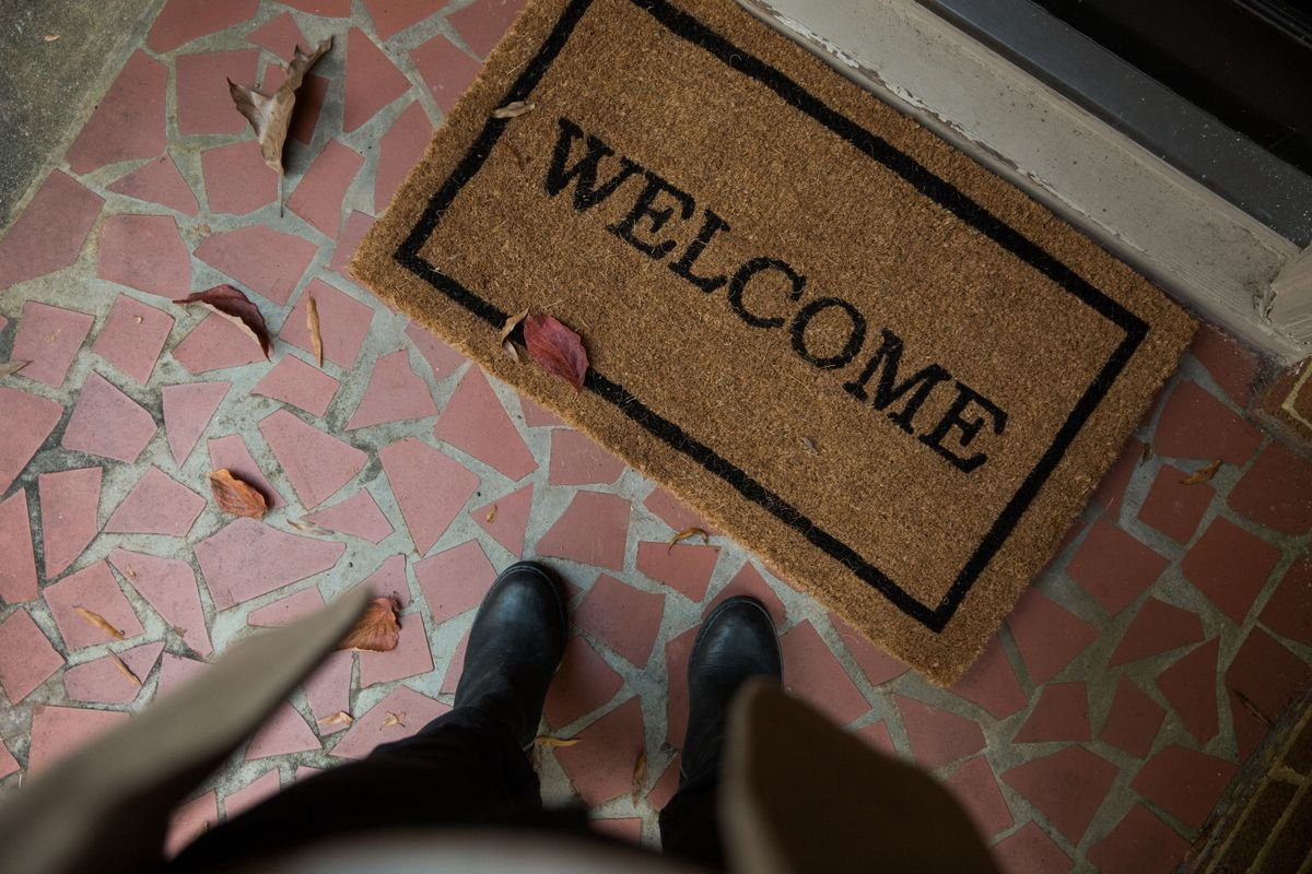 Welcome doormat at a front door with autumn leaves