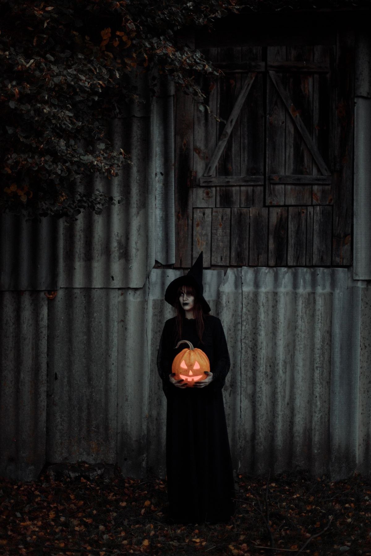 Witch holding a carved pumpkin for Halloween home entrance decor