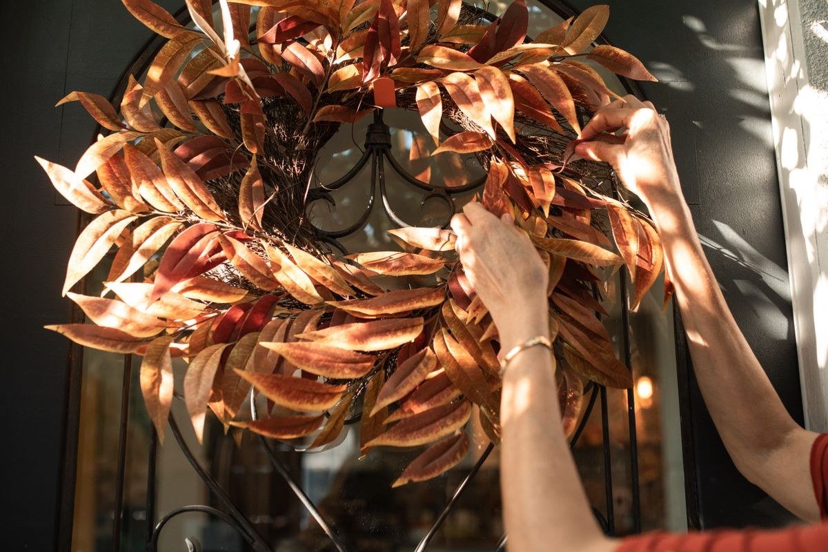 Autumn wreath being hung on a front door for seasonal Halloween decor